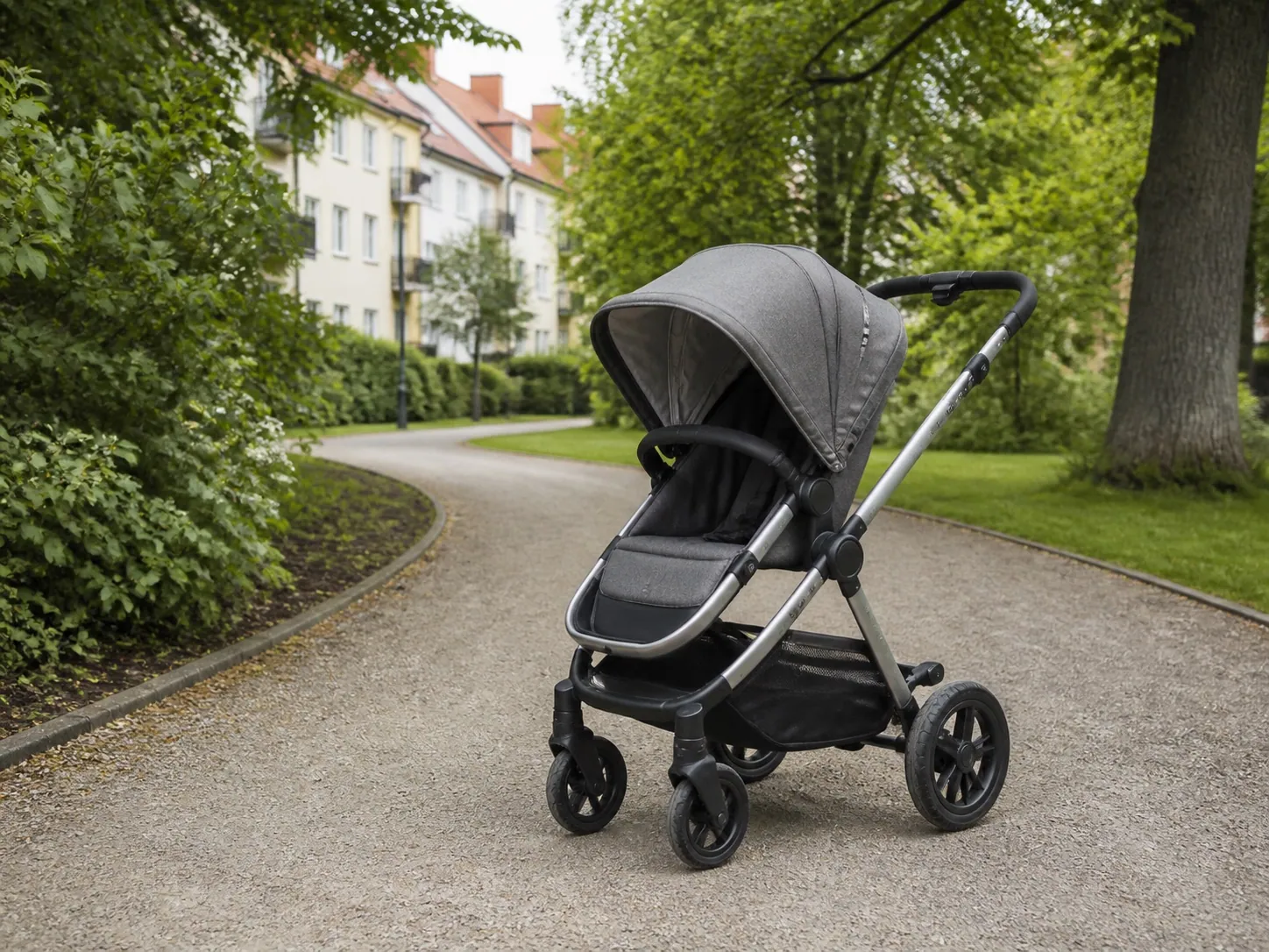 Modern duobarnvagn på en svensk gångväg med park och bostadshus i bakgrunden.