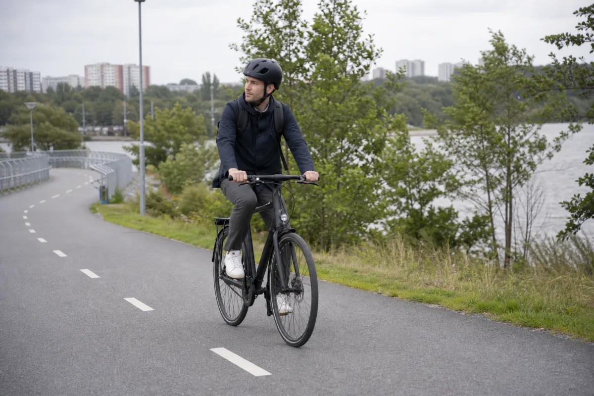 Cyklist med välpassande cykelhjälm på en svensk cykelväg.