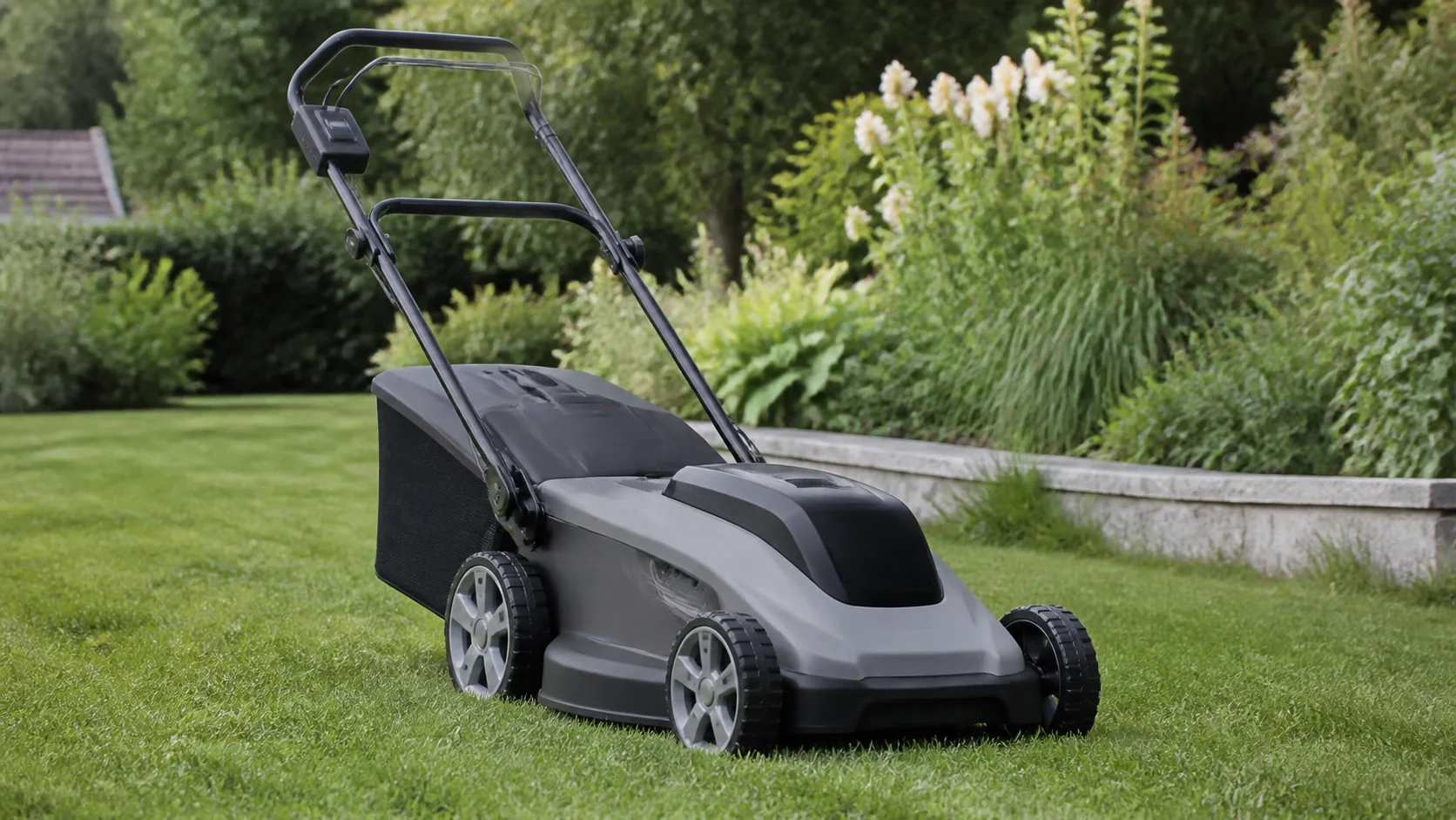 Batteridriven gräsklippare på en svensk villagräsmatta i mjukt dagsljus.