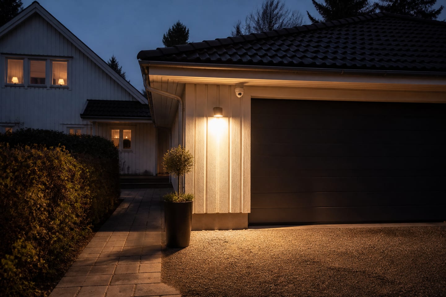 Upplyst garageuppfart fotograferad av en utomhuskamera i mörker.