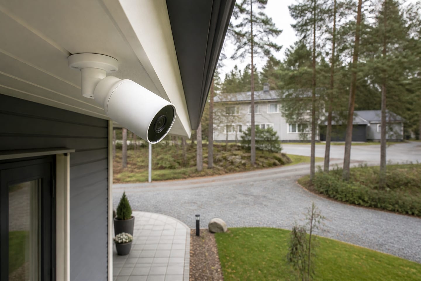 Vit utomhuskamera utan synligt varumärke monterad under takfot vid en svensk villa.